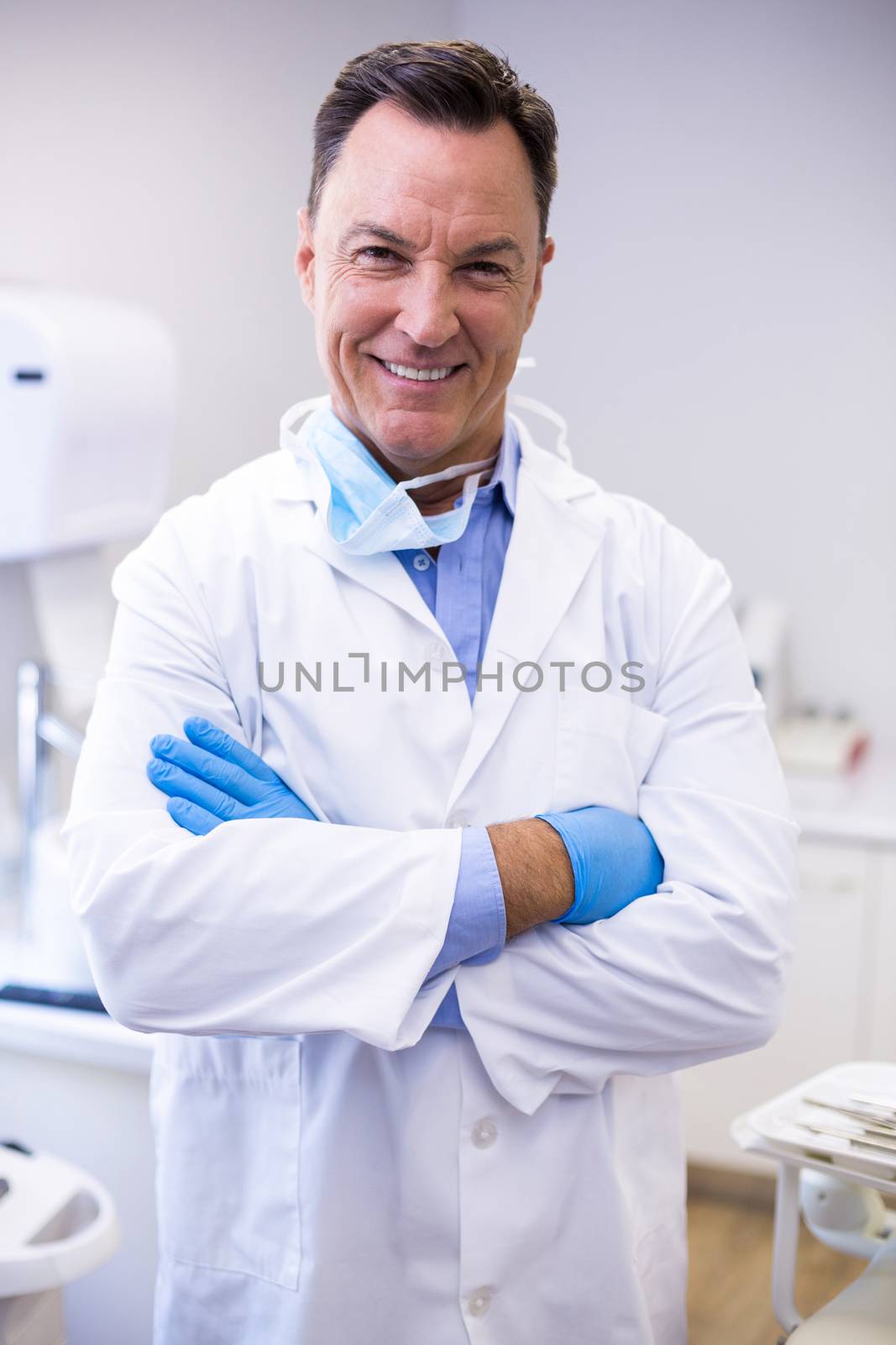 Smiling dentist standing with arms crossed at dental clinic by Wavebreakmedia