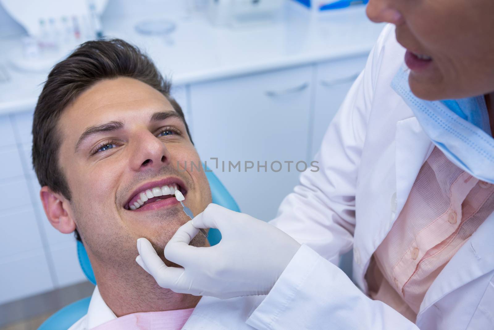 Dentist holding medical equipment while examining patient at medical clinic by Wavebreakmedia