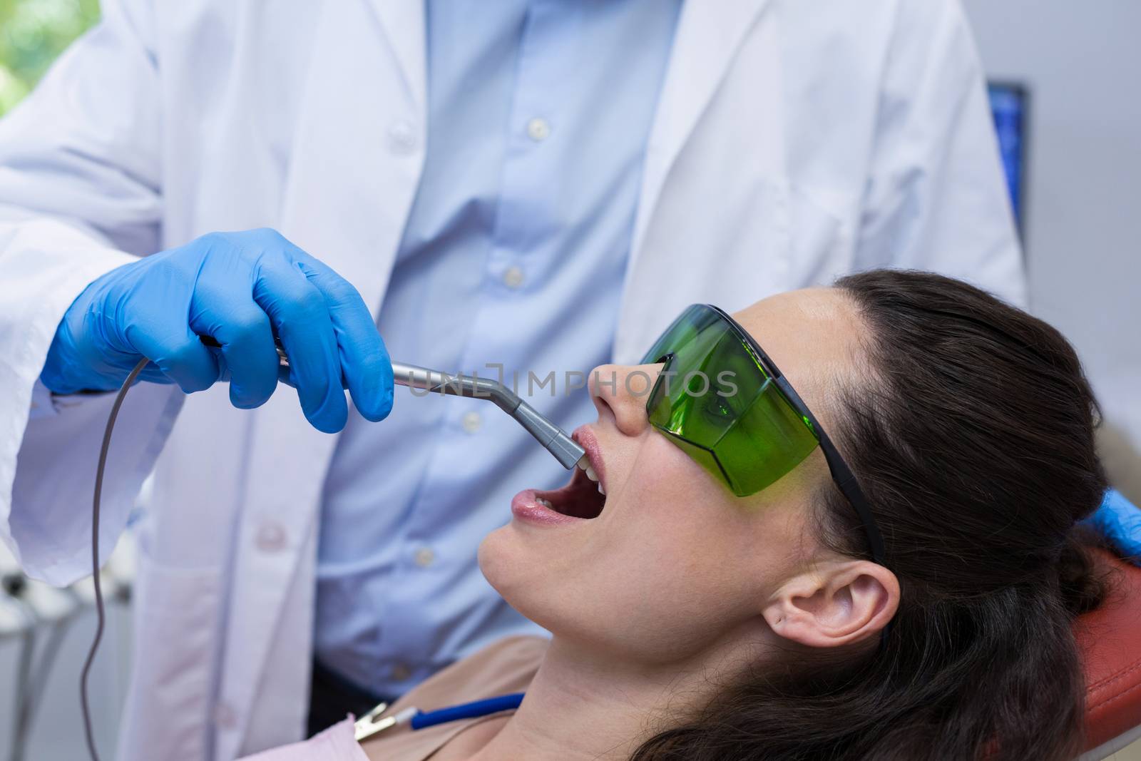 Dentist examining a female patient with dental equipment by Wavebreakmedia