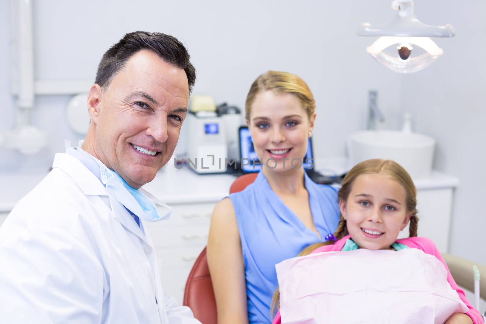 Portrait of dentist with young patient and his mother by Wavebreakmedia