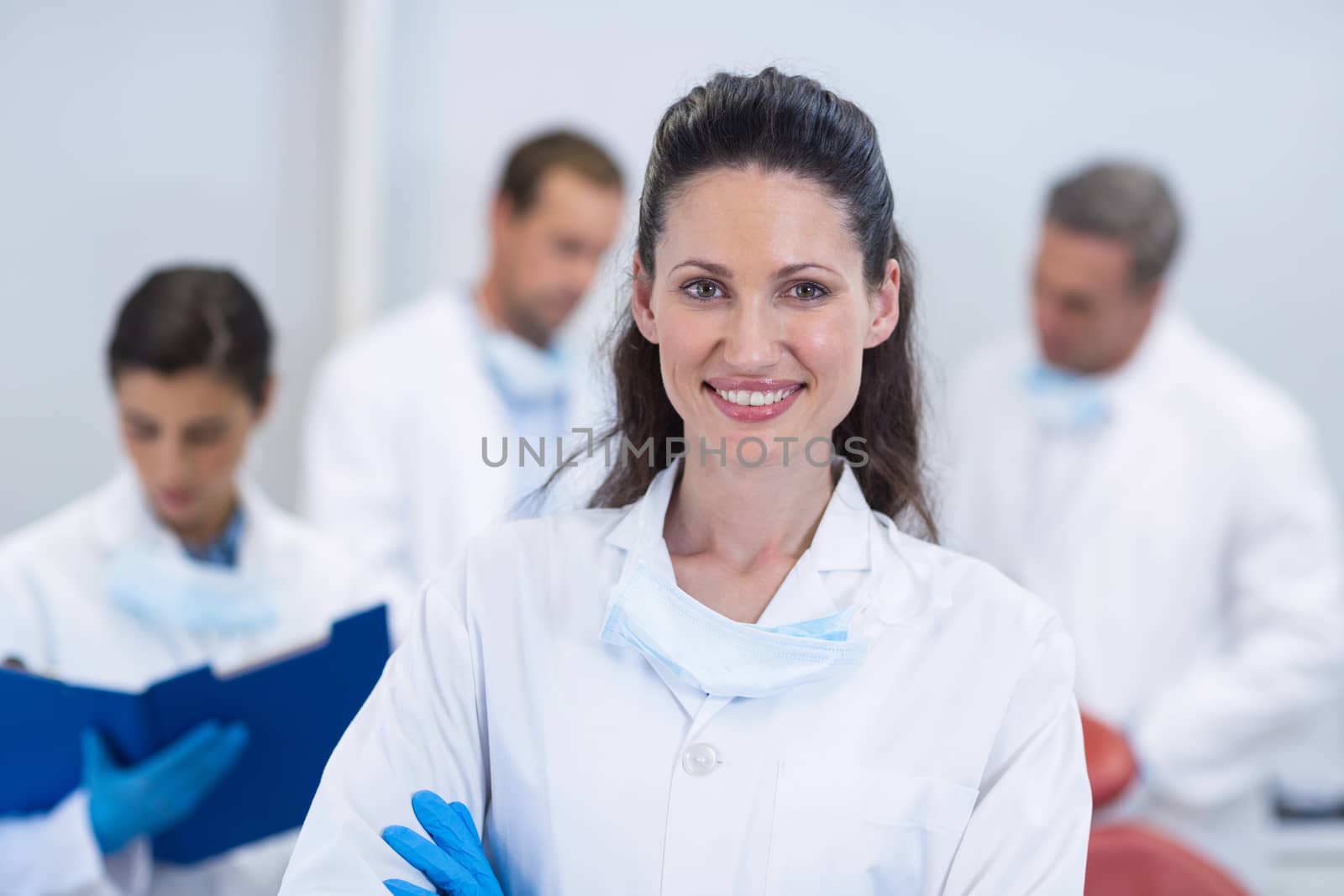 Smiling dentist standing with arms crossed by Wavebreakmedia