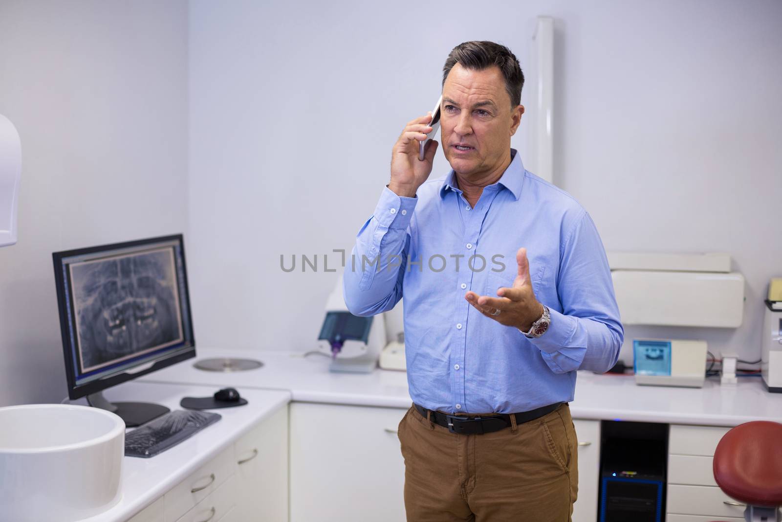 Dentist talking on mobile phone at dental clinic