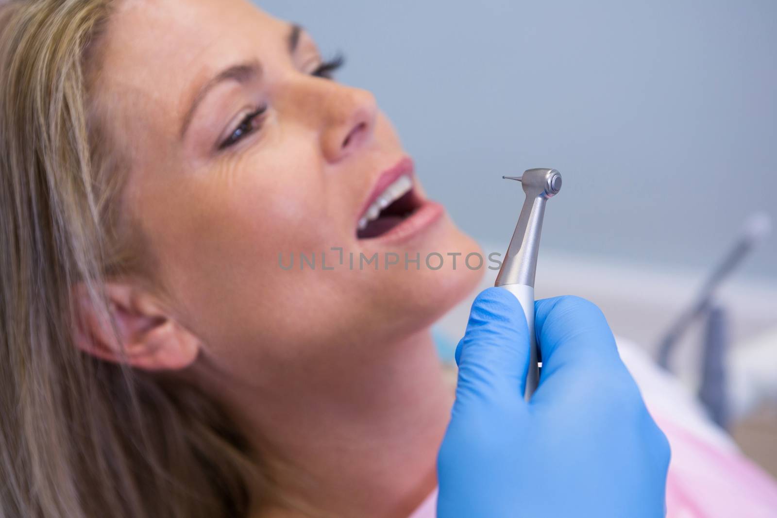 Cropped image of dentist holding medical equipment while giving treatment to patient by Wavebreakmedia