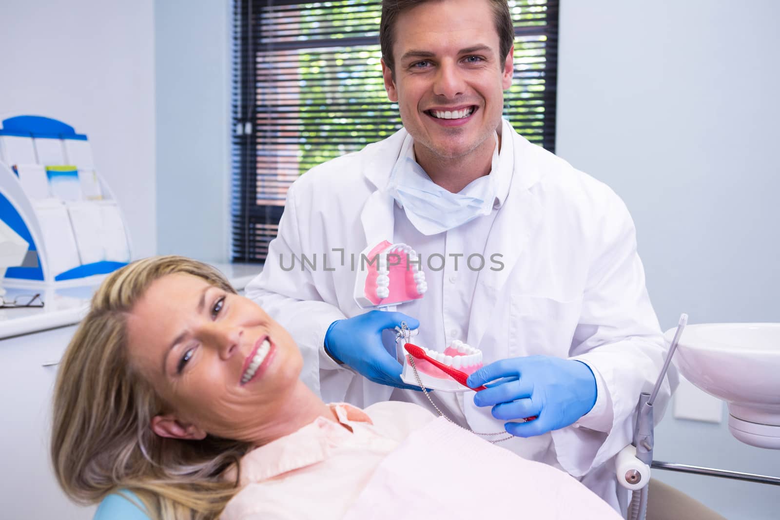 Happy dentist holding dental mould by woman at medical clinic by Wavebreakmedia