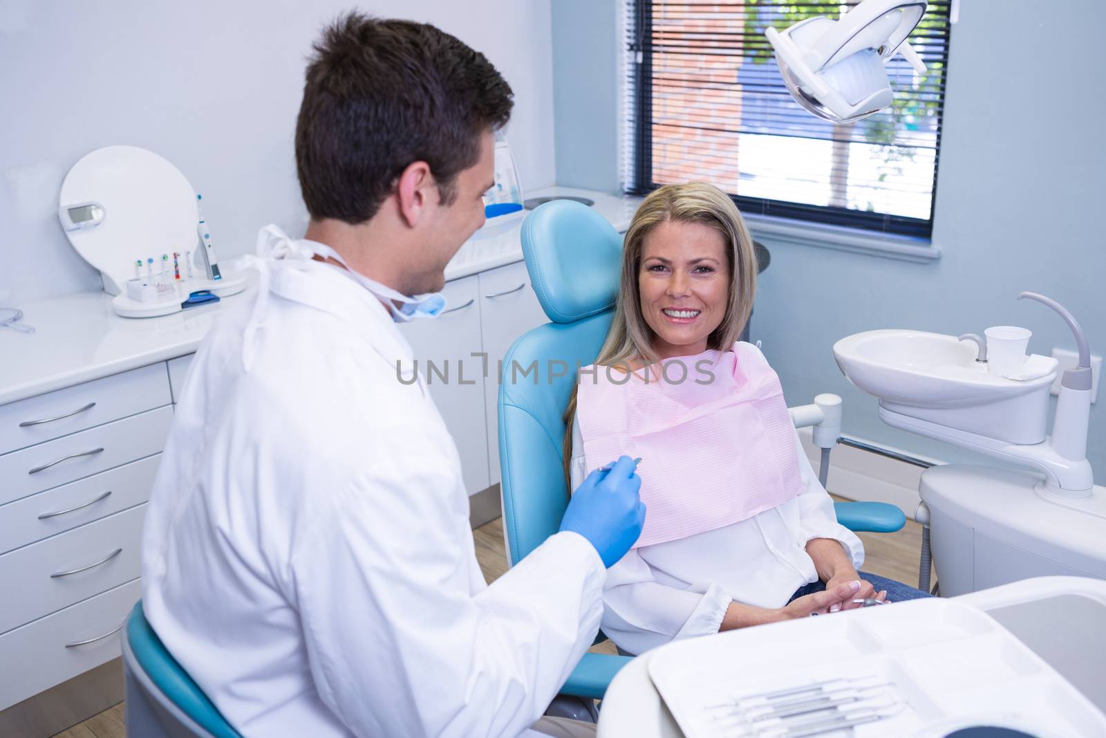 Smiling patient discussing with dentist at dental clinic