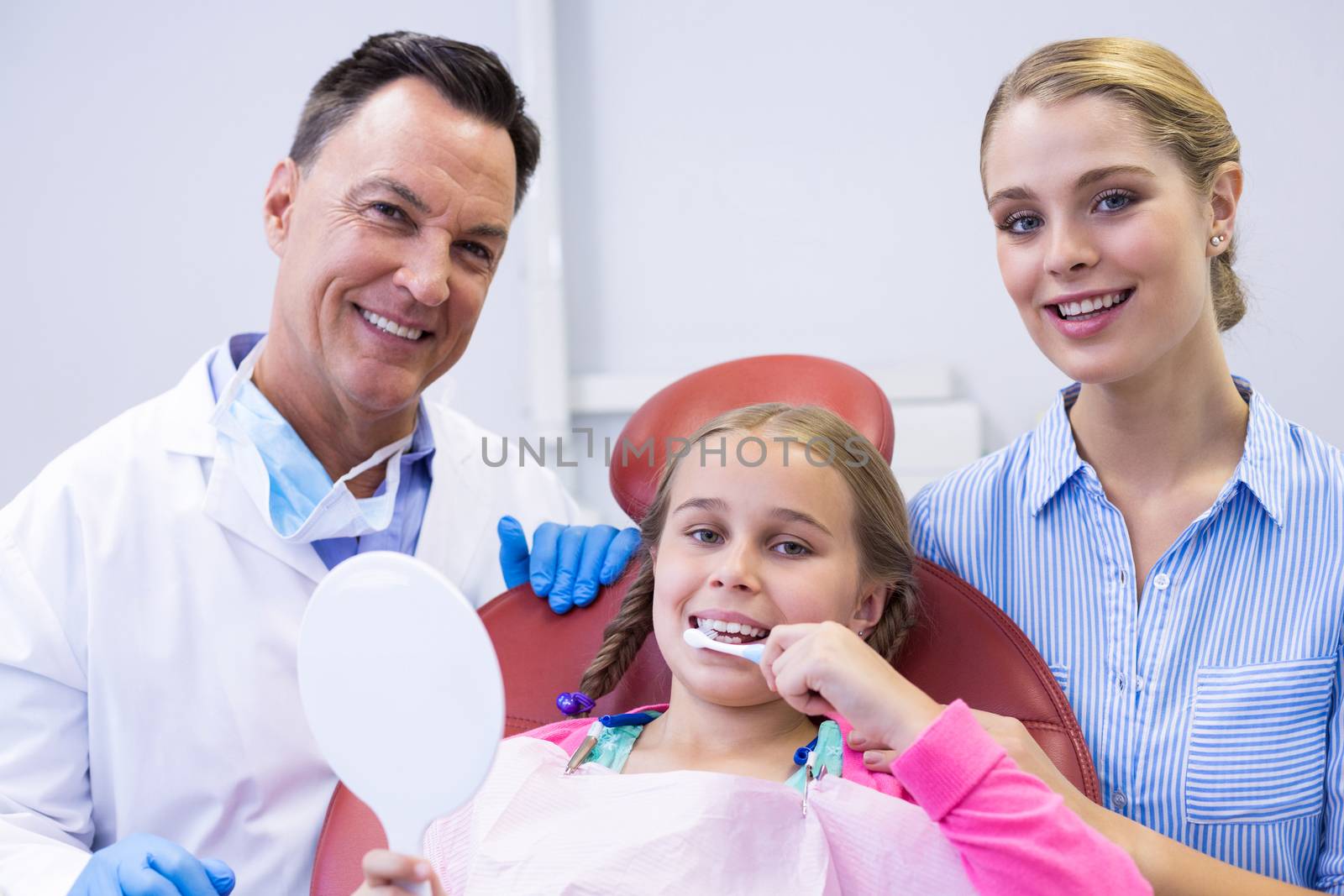 Portrait of dentist with young patient and his mother at dental clinic