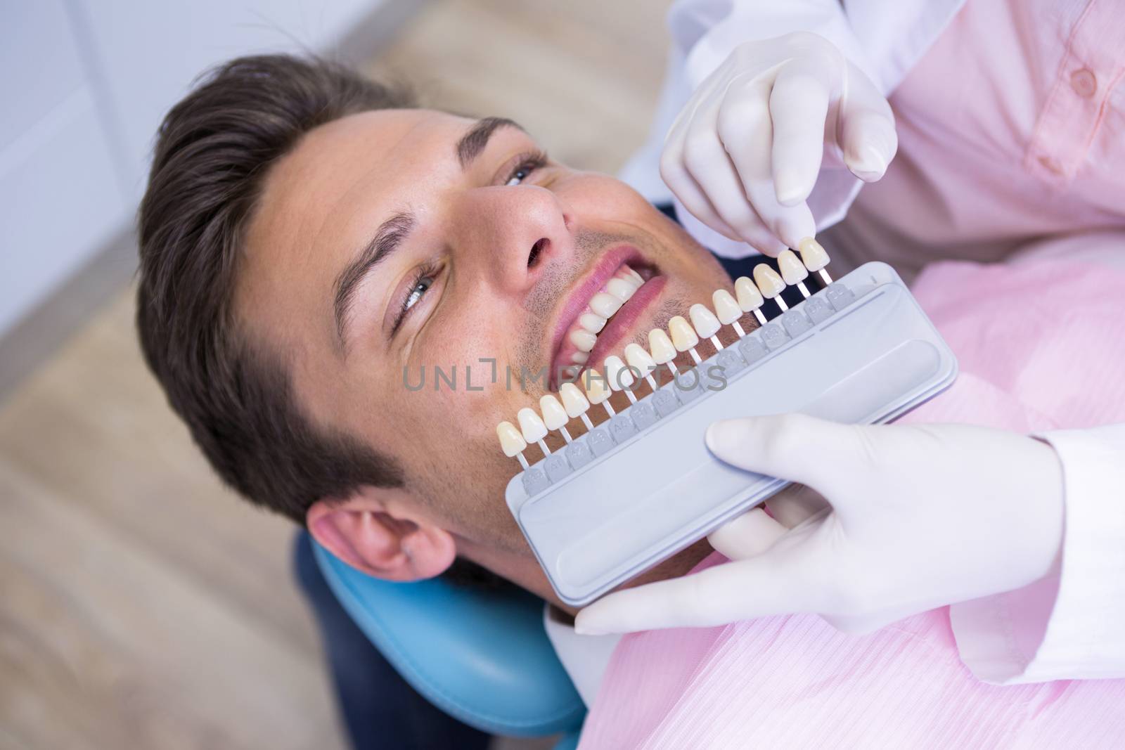 High angle view of dentist holding equipment while examining patient by Wavebreakmedia
