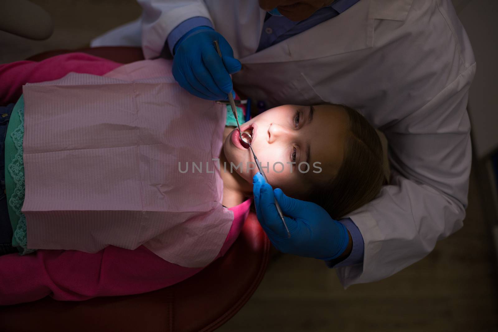 Dentist examining a young patient with tools at dental clinic