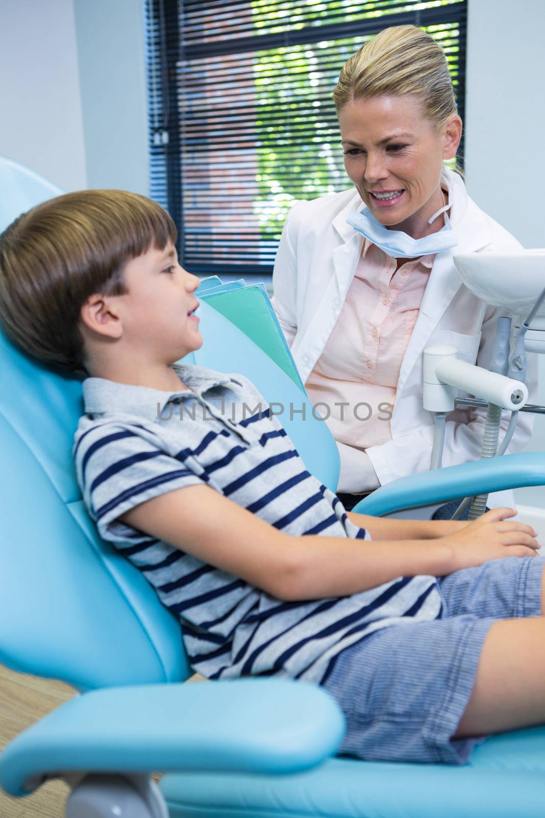 Smiling dentist talking with boy at medical clinic