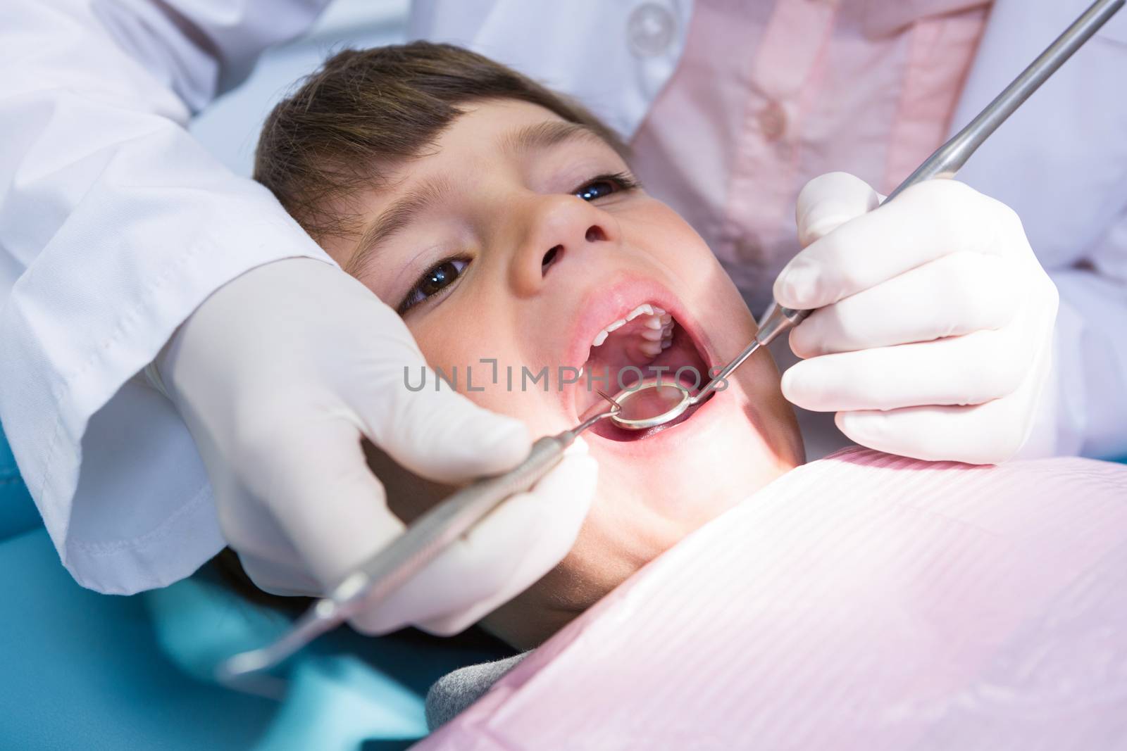 Dentist examining boy mouth at medical clinic by Wavebreakmedia