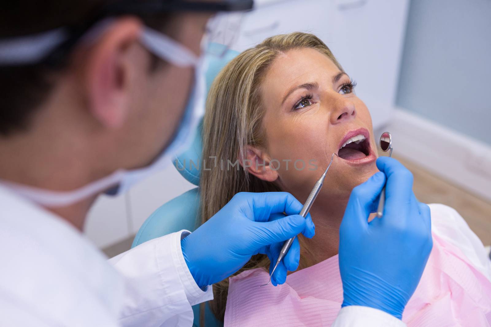 Close up of dentist examining woman mouth at clinic