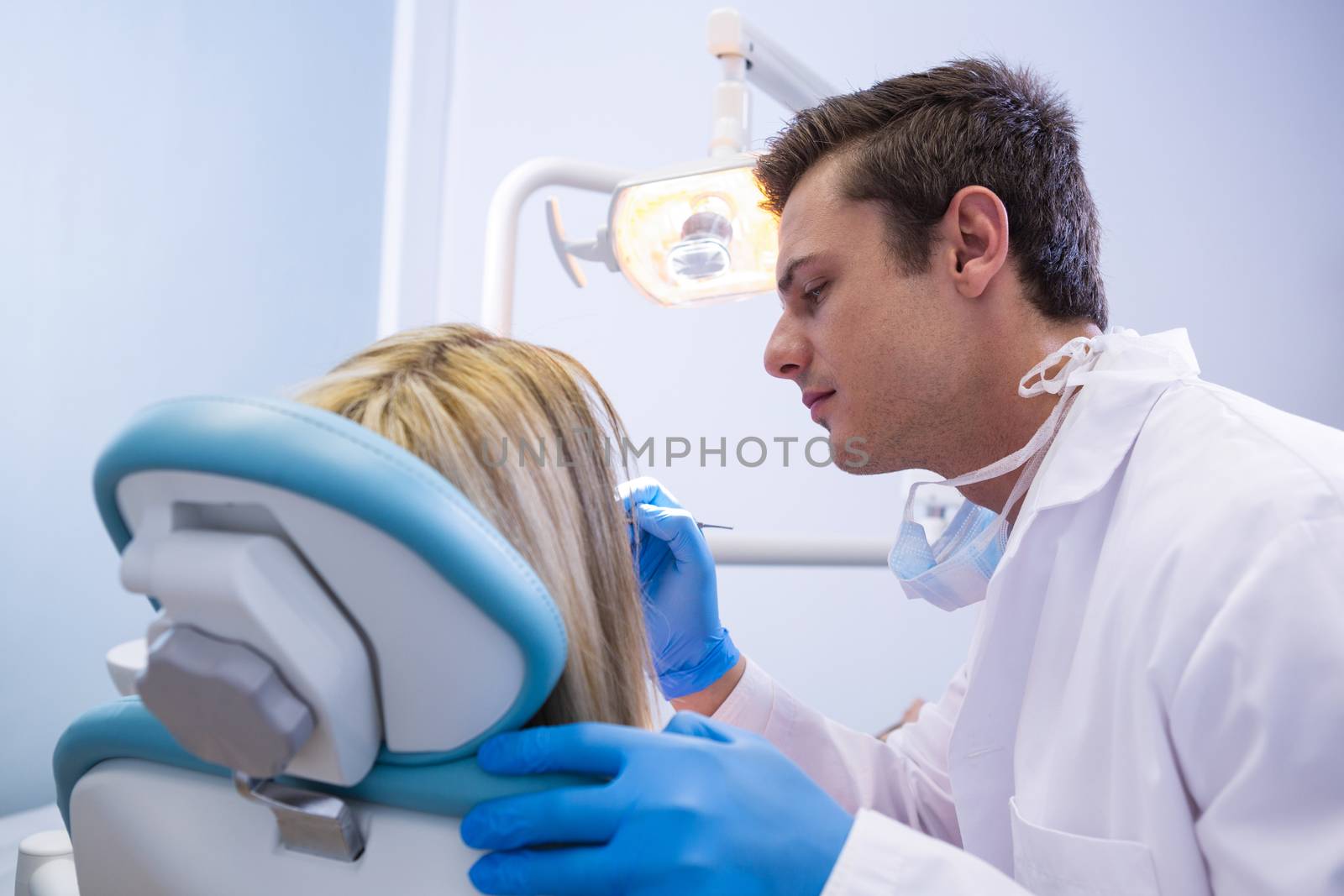 Side view of dentist polishing woman teeth at dental clinic