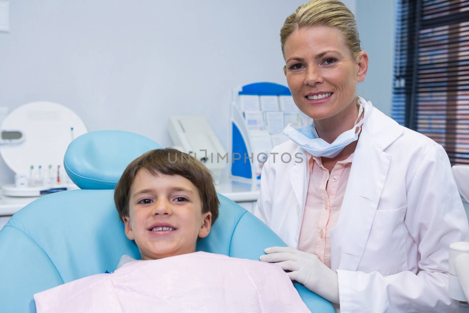 Portrait of boy sitting on chair by dentist at clinic