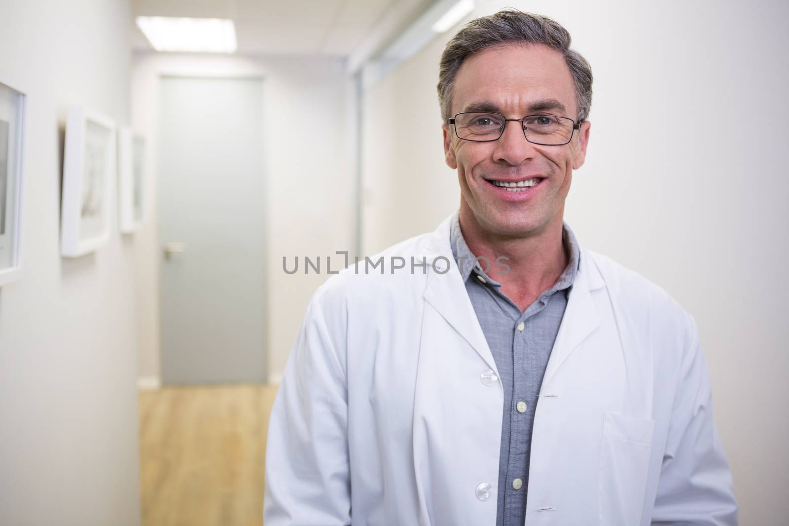 Portrait of smiling dentist standing at lobby in dental clinic