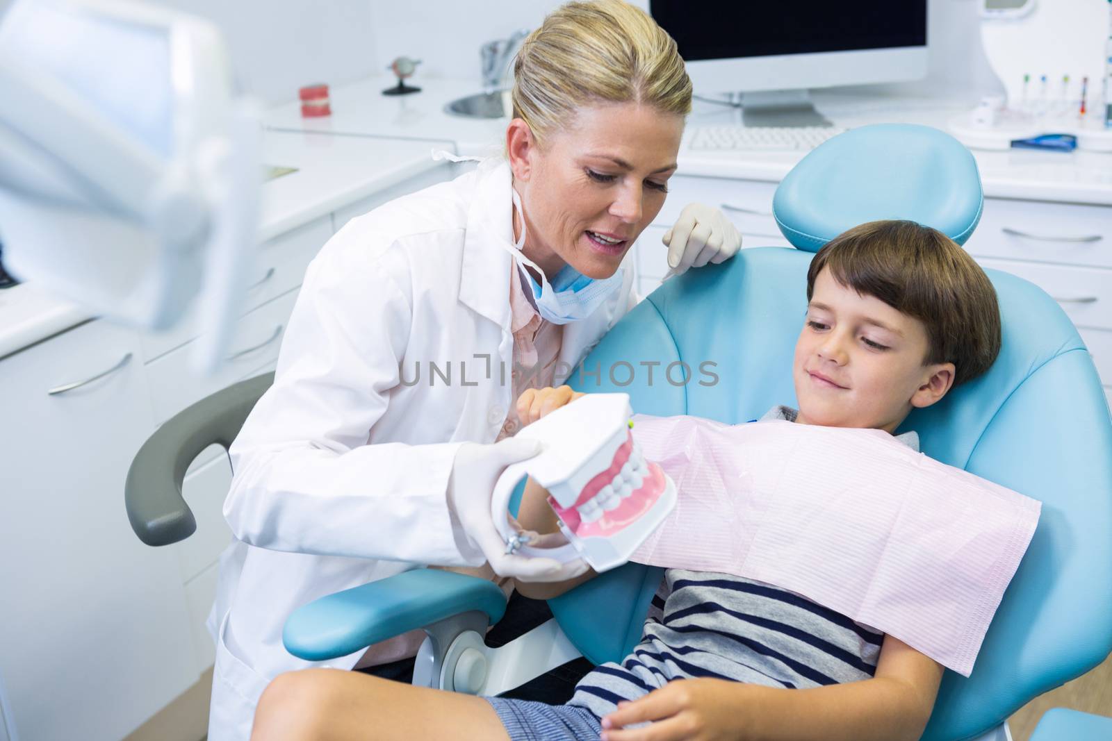 Dentist holding dental mould while talking with boy at clinic