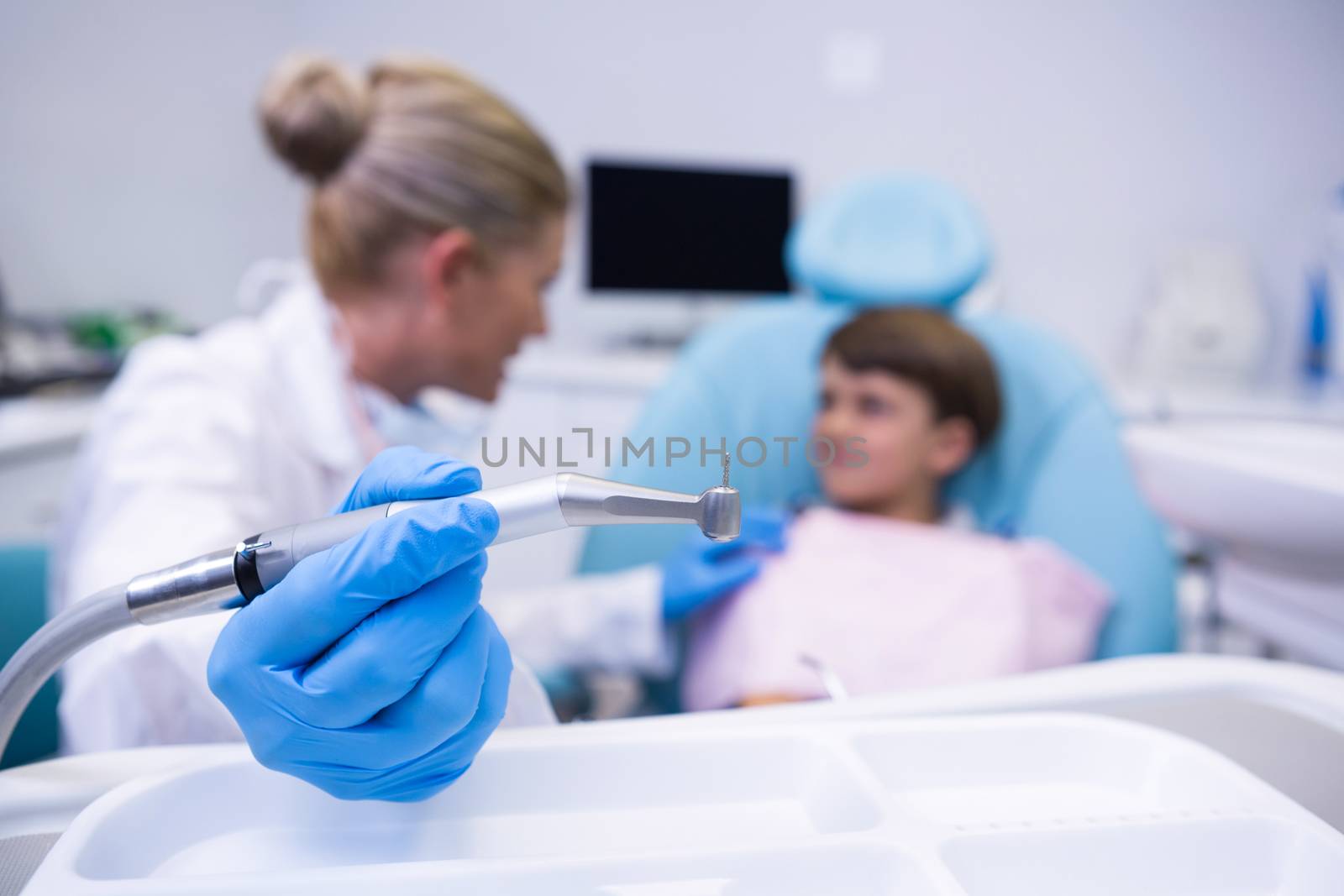 Close up of dentist holding medical equipment while examining boy by Wavebreakmedia