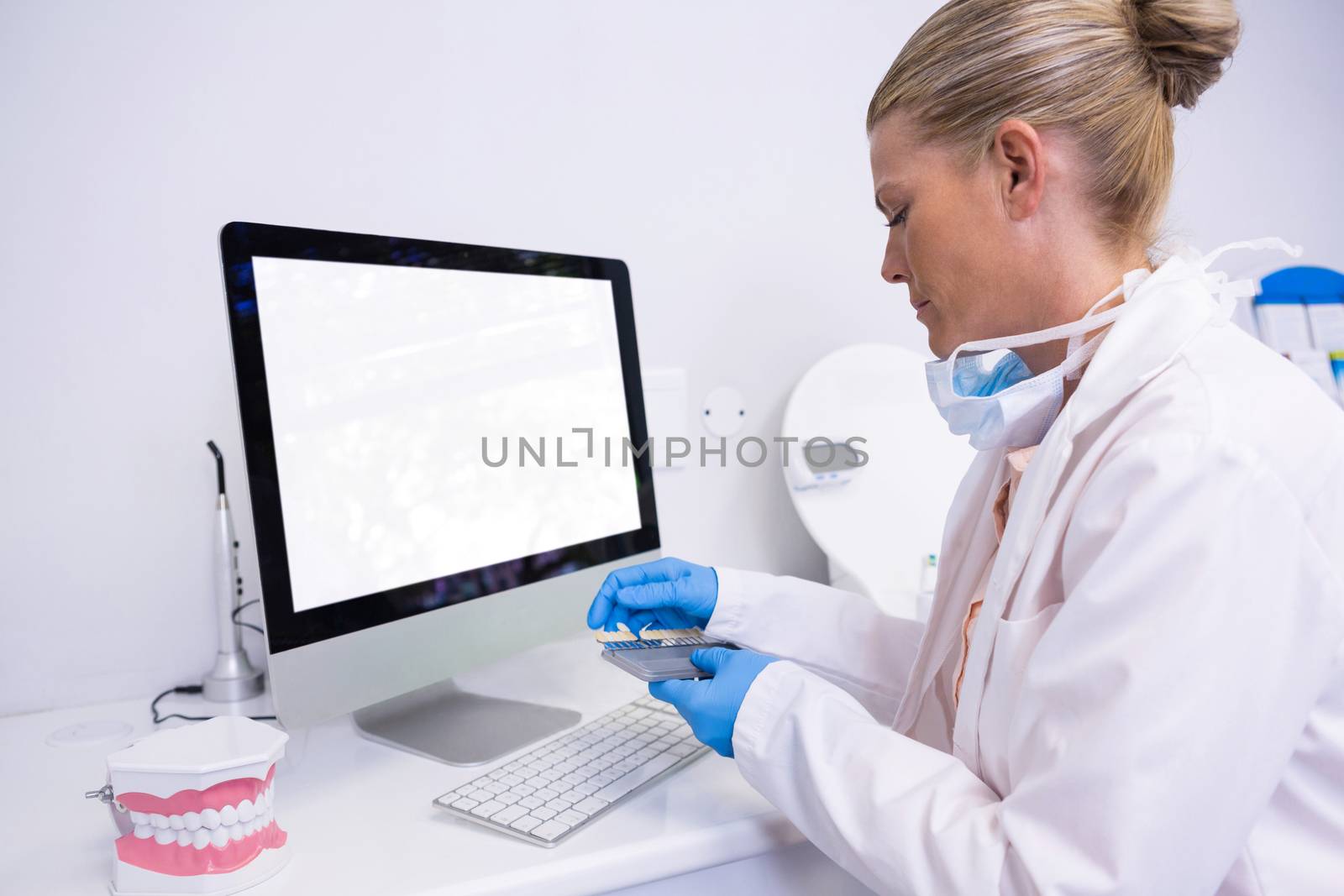 Side view of dentist working while sitting by computer at clinic