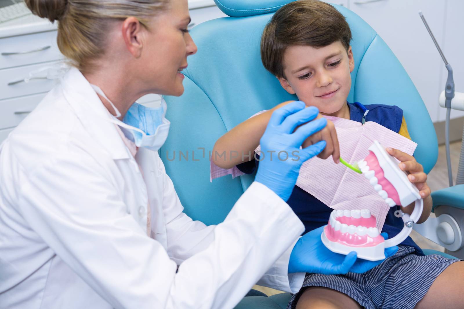 Dentist looking at boy brushing dentures by Wavebreakmedia