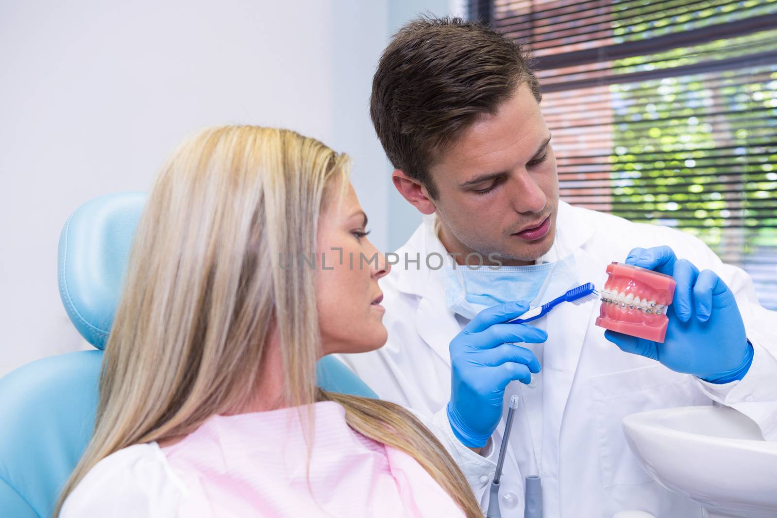 Dentist showing dental mold to woman at medical clinic