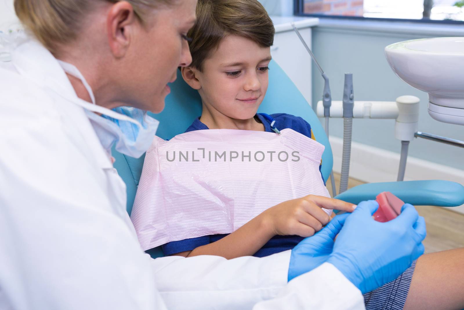 Dentist and boy looking at dentures by Wavebreakmedia