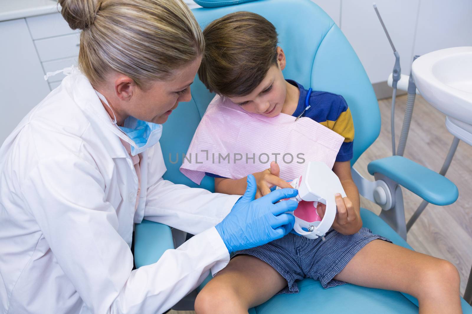 High angle view of dentist teaching boy brushing teeth of dentures at medical clinic