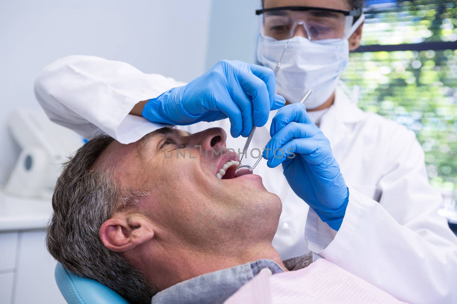 Happy man receiving dental treatment by dentist by Wavebreakmedia