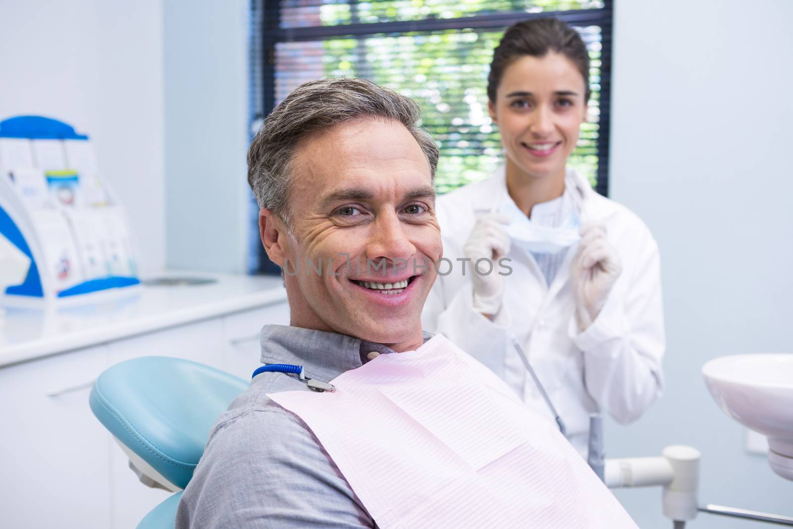 Portrait of man sitting on chair by dentist at clinic