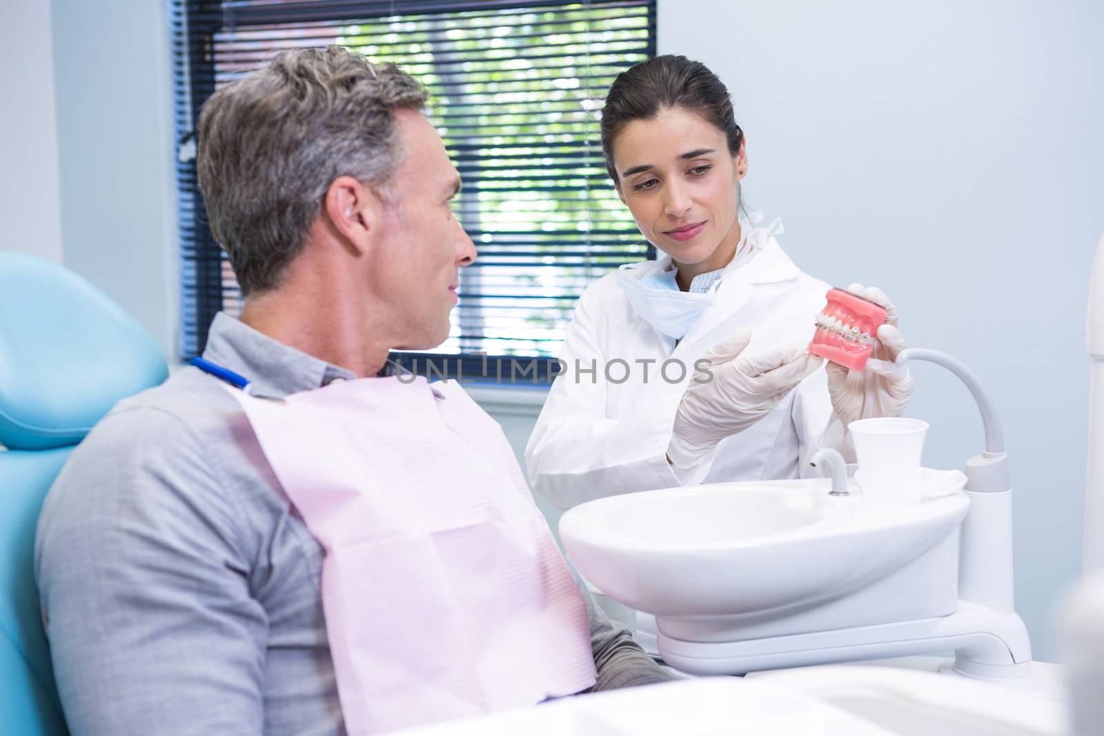 Happy dentist showing dental mold to man by Wavebreakmedia