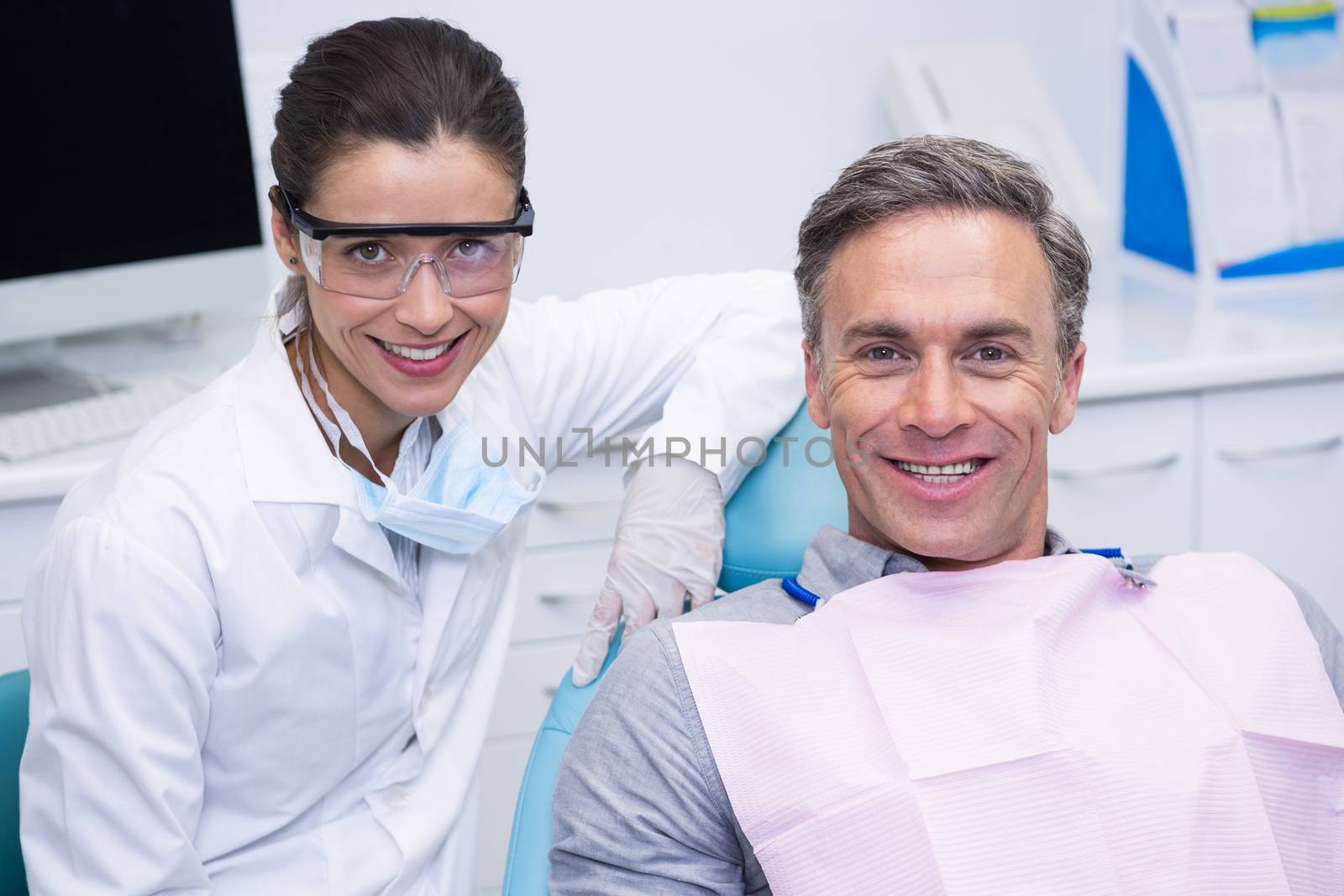 Smiling dentist by patient at medical clinic by Wavebreakmedia