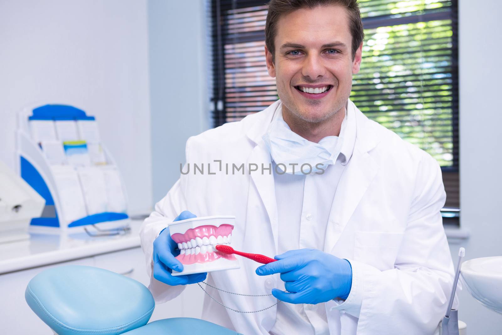 Portrait of dentist brushing dental mold while sitting at clinic