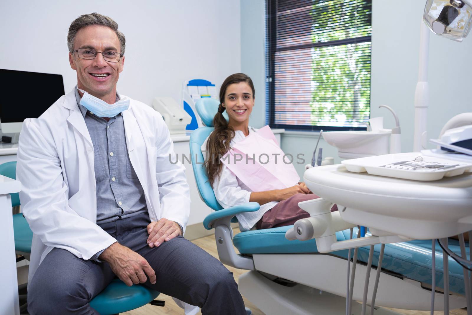 Portrait of smiling dentist and patient standing on chair at medical clinic