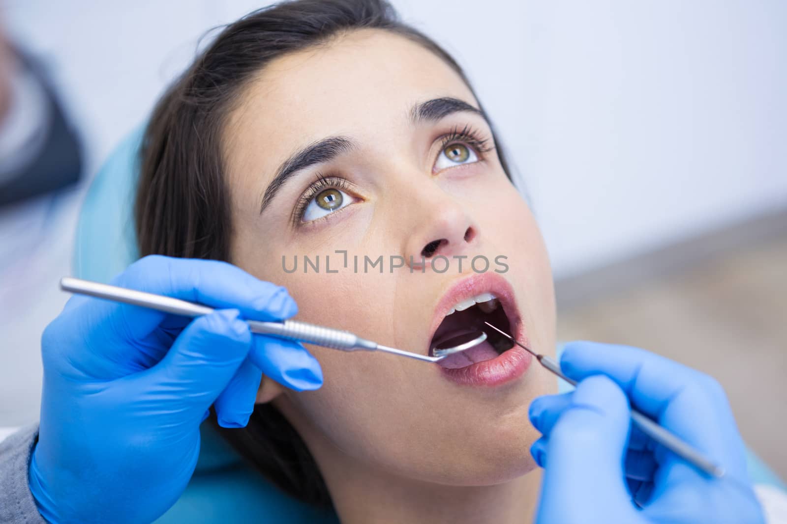 Dentist holding equipments while examining woman at medical clinic by Wavebreakmedia