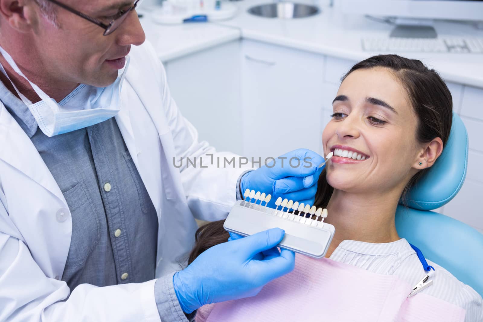 Dentist holding equipment while examining woman at clinic by Wavebreakmedia