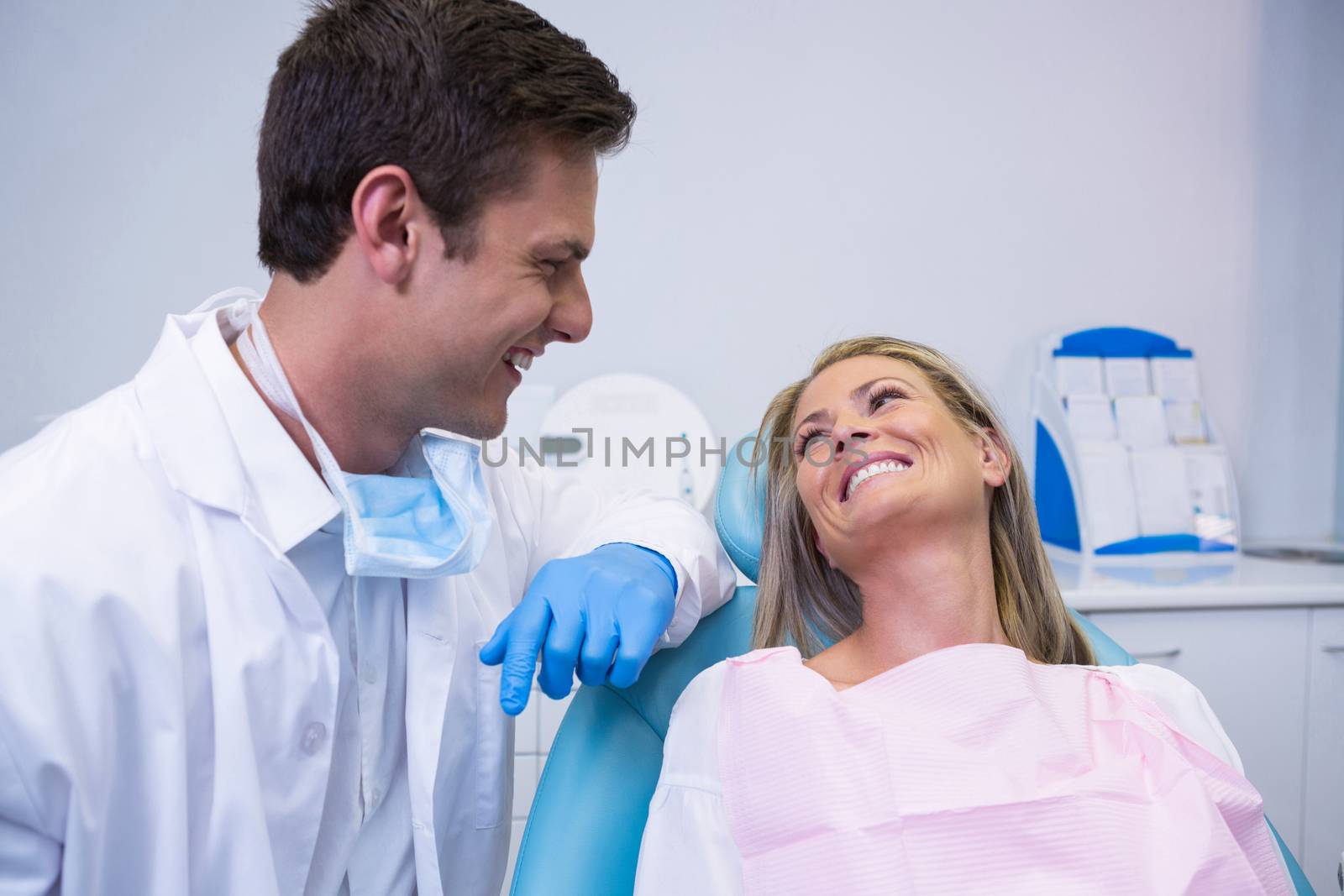 Smiling patient looking at dentist while sitting on chair by Wavebreakmedia