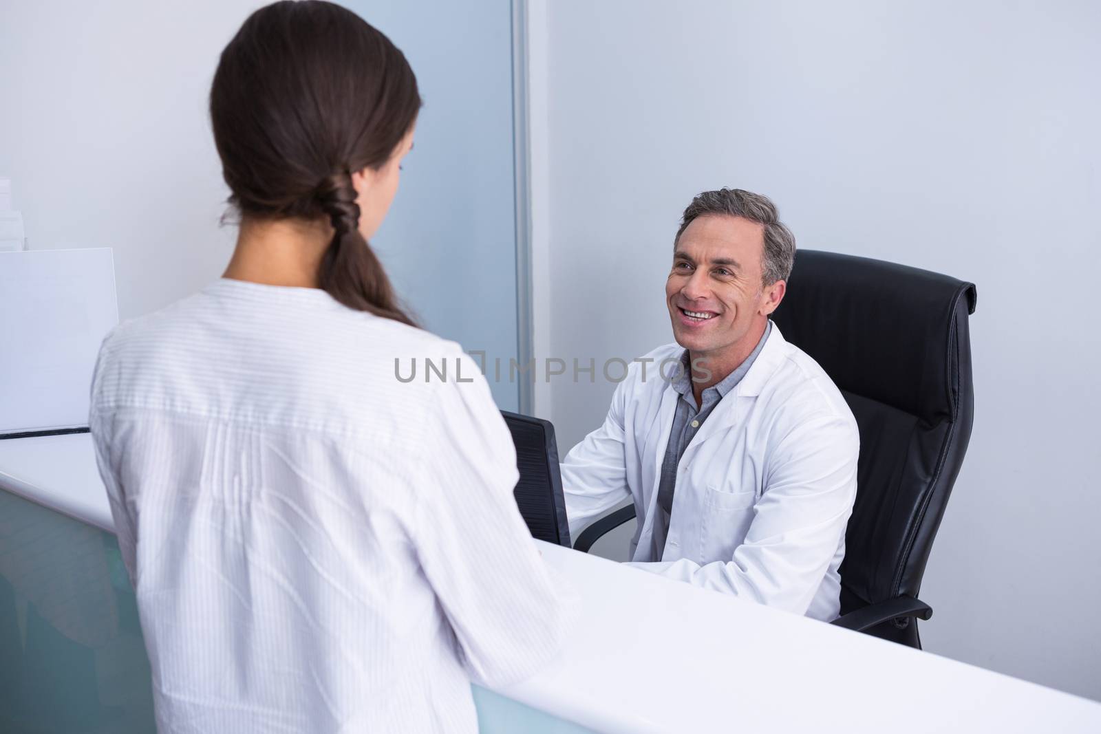 Happy dentist and woman talking in cabin against wall
