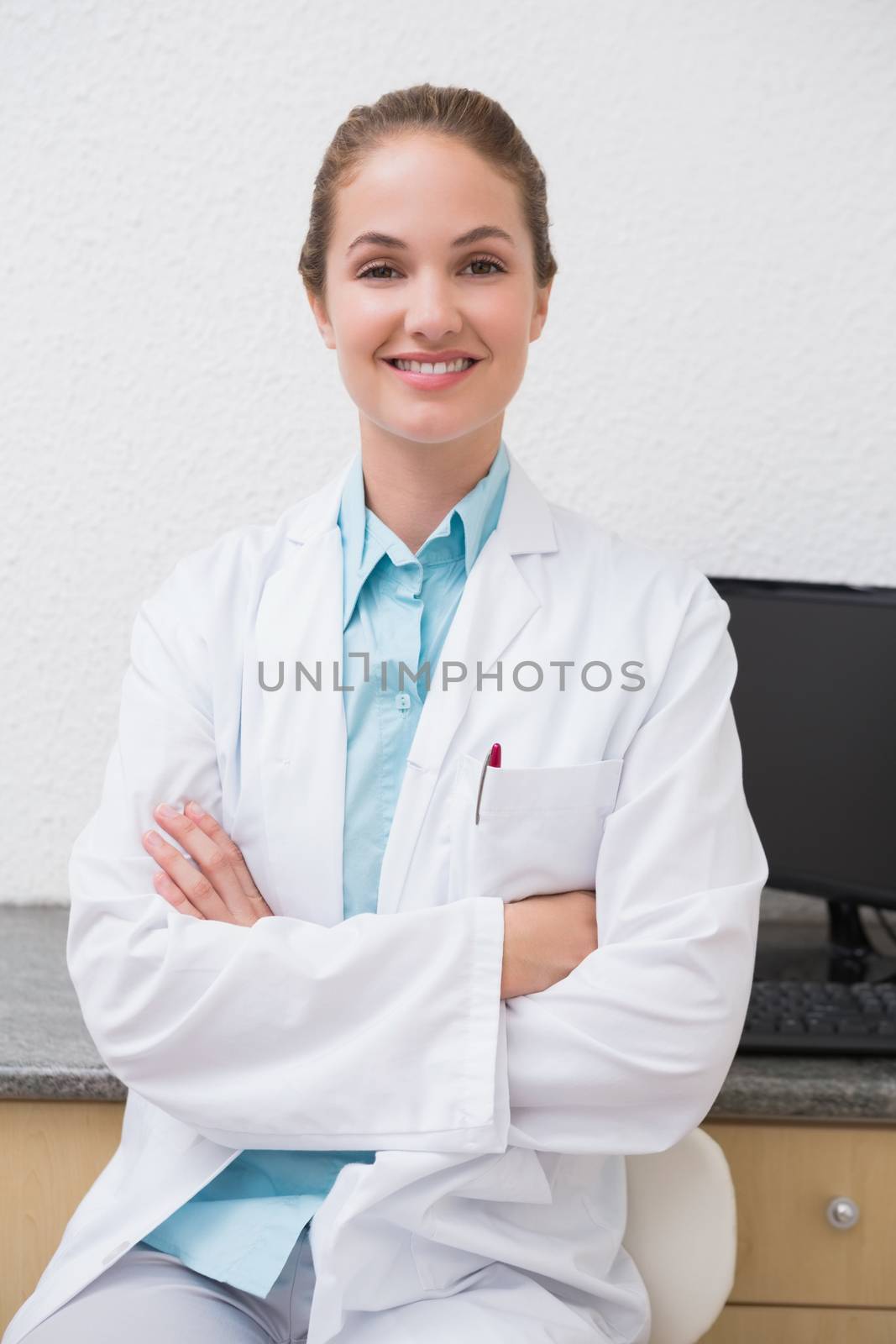 Dentist sitting at desk smiling at camera by Wavebreakmedia
