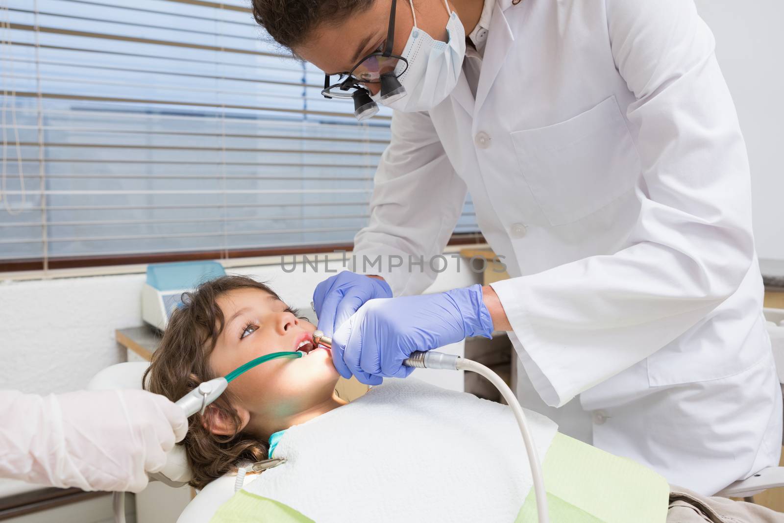 Pediatric dentist examining a little boys teeth in the dentists chair by Wavebreakmedia