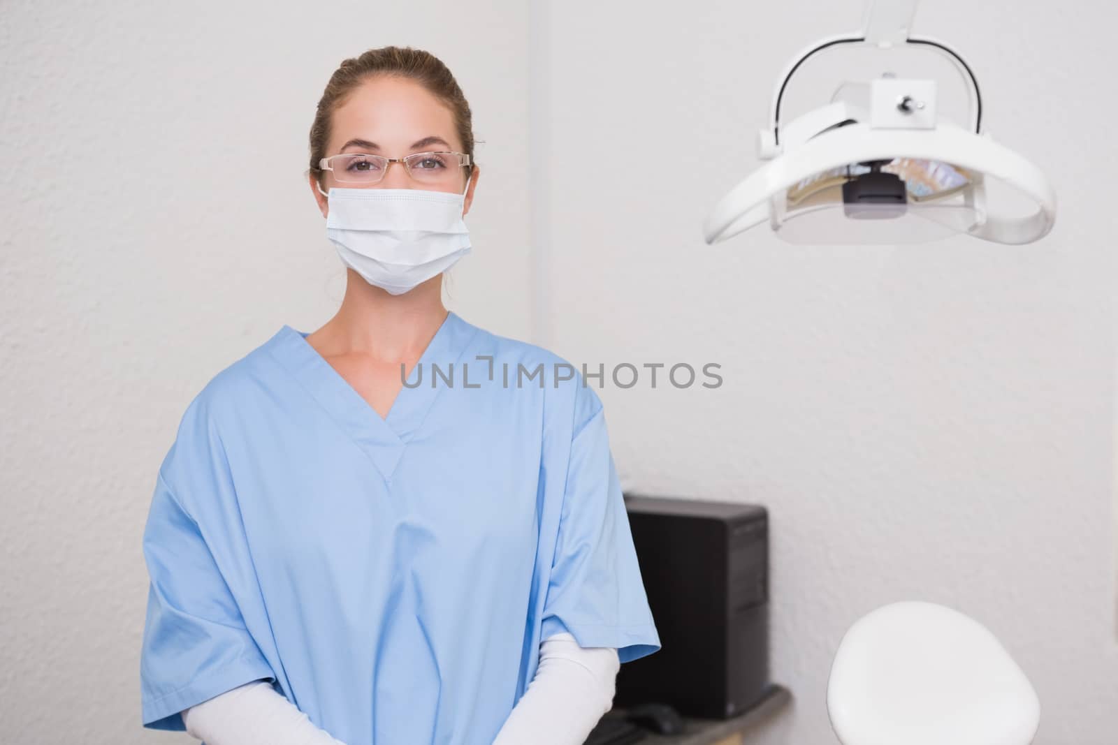 Dentist in blue scrubs looking at camera in mask at the dental clinic