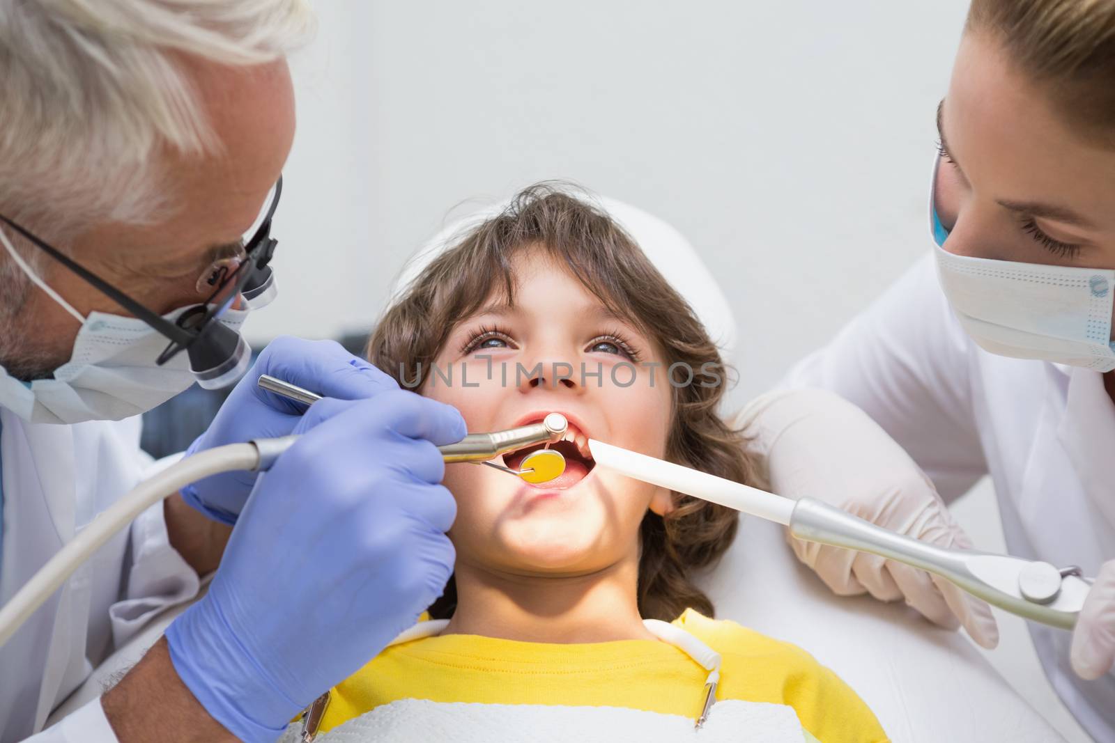 Pediatric dentist and assistant examining a little boys teeth at the dental clinic