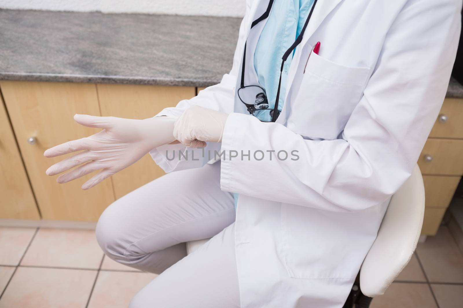 Dentist pulling on surgical gloves at the dental clinic