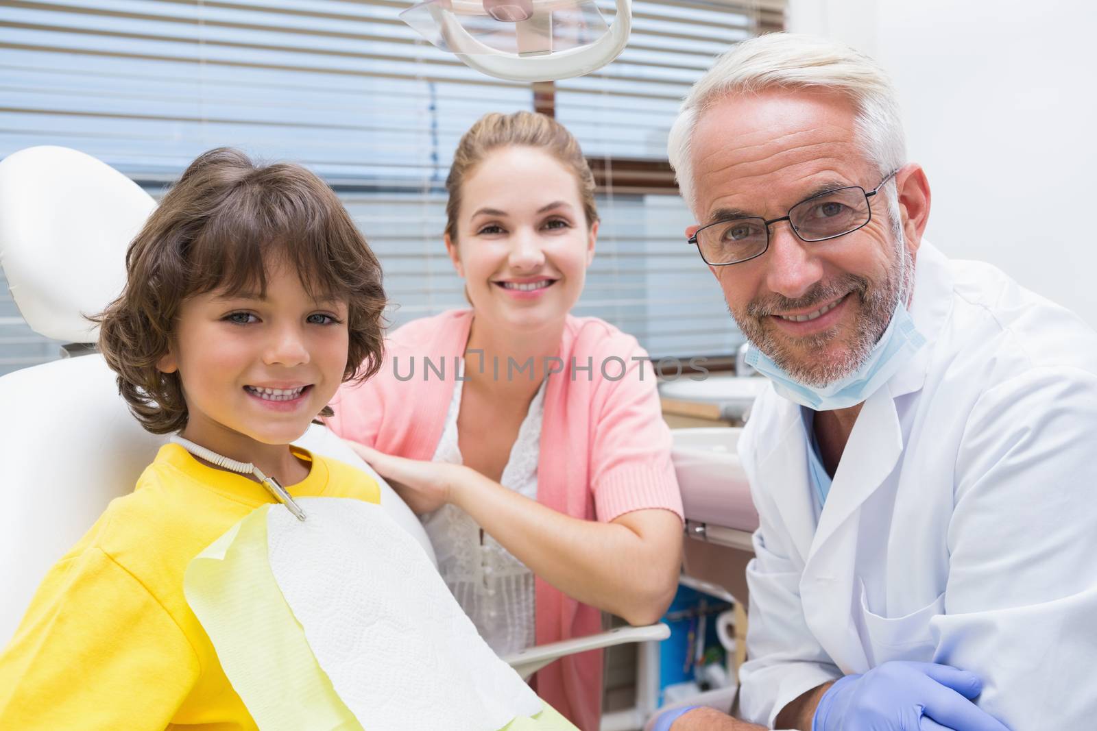 Little boy smiling at camera with mother and dentist beside him by Wavebreakmedia
