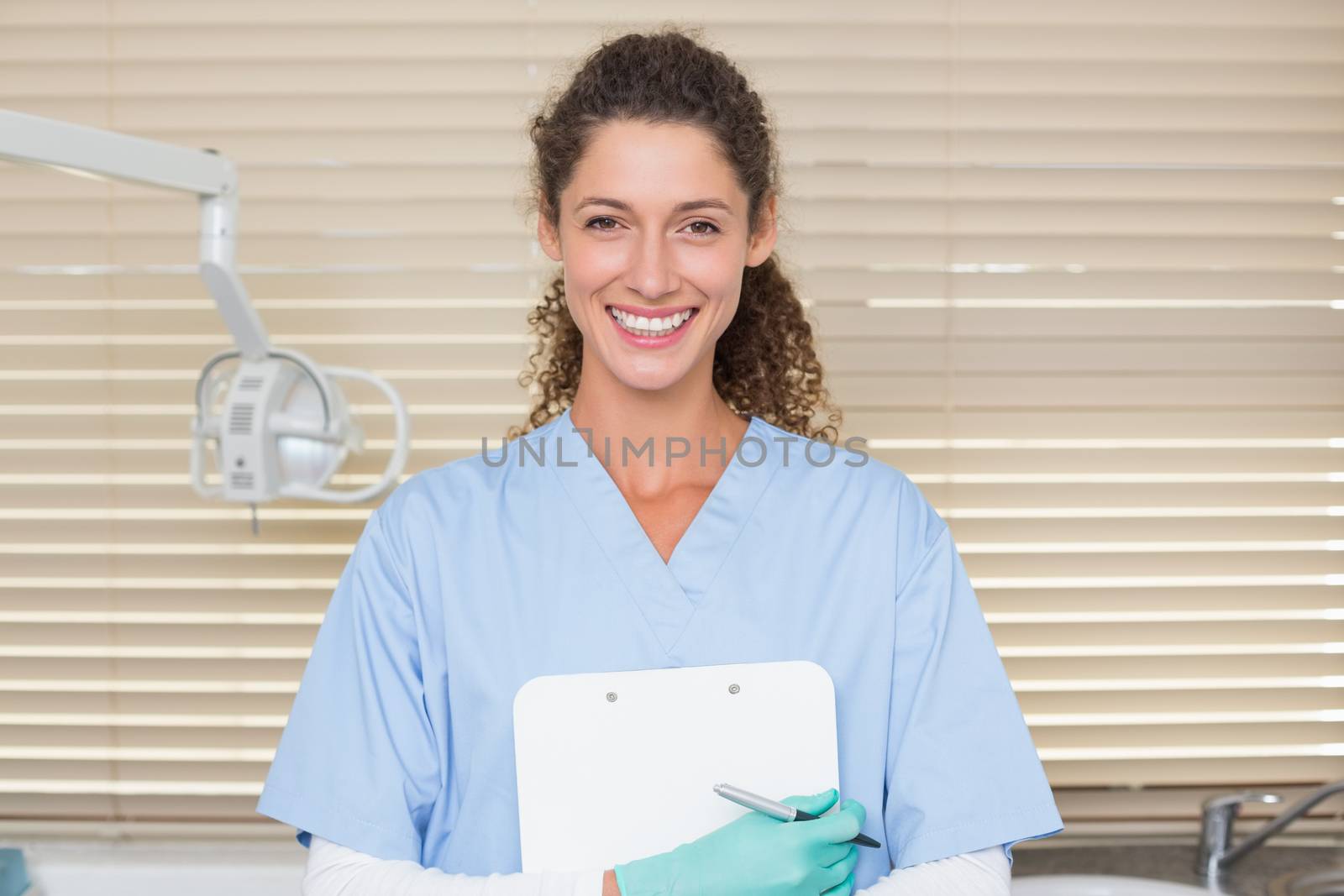 Dentist in blue scrubs holding clipboard at the dental clinic