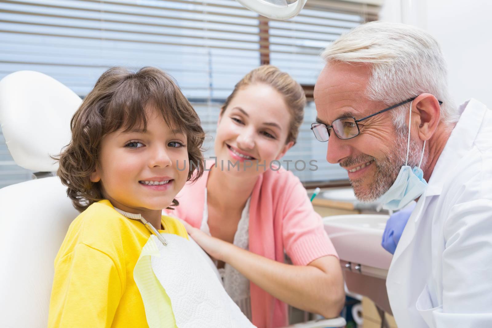 Little boy smiling at camera with mother and dentist beside him by Wavebreakmedia