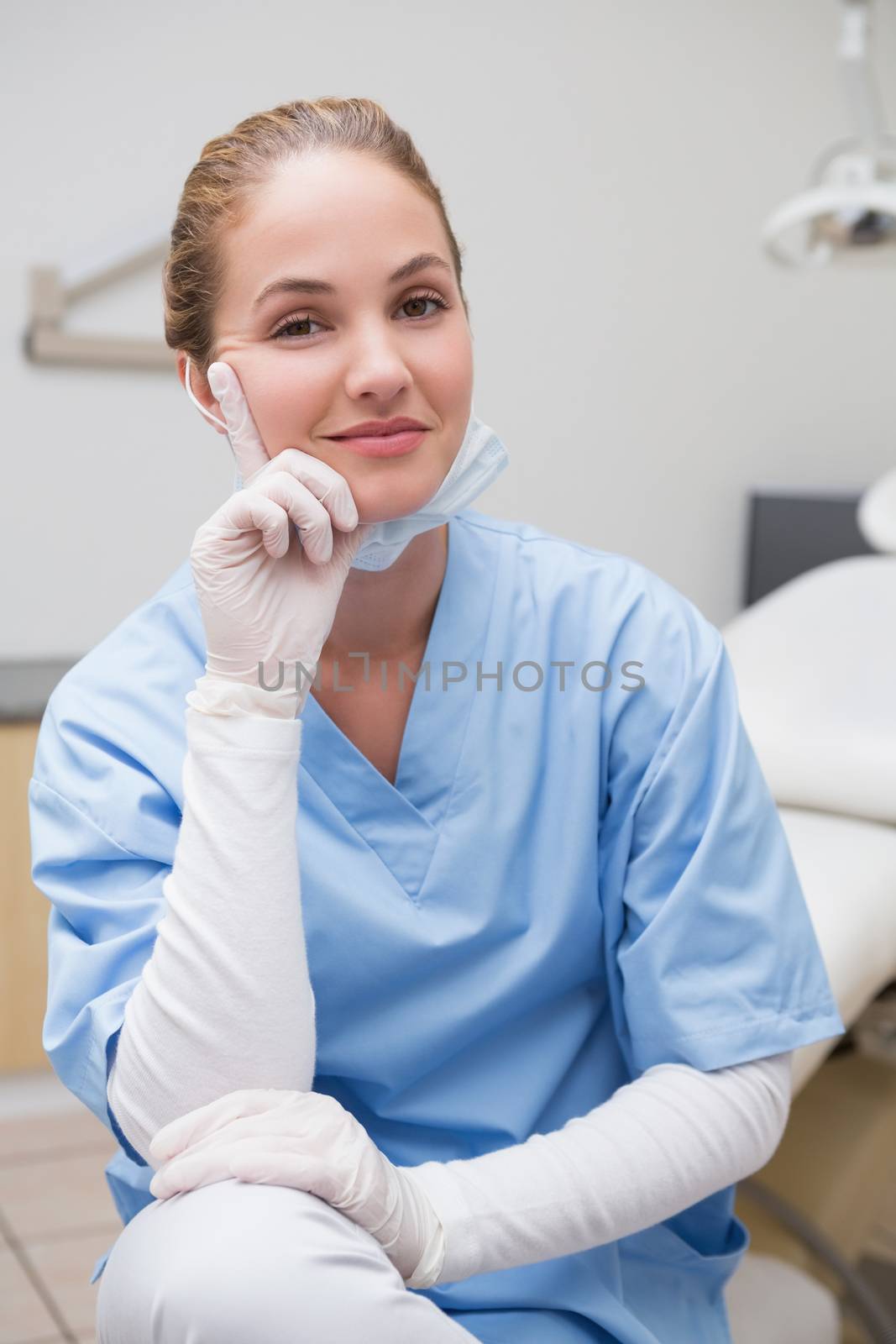 Dentist in blue scrubs smiling at camera at the dental clinic