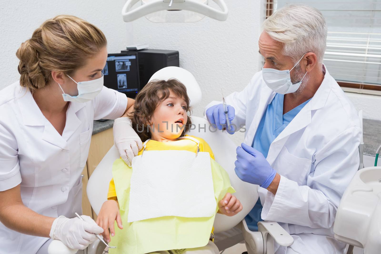 Terrified little boy looking at needle in dentists chair at the dental clinic
