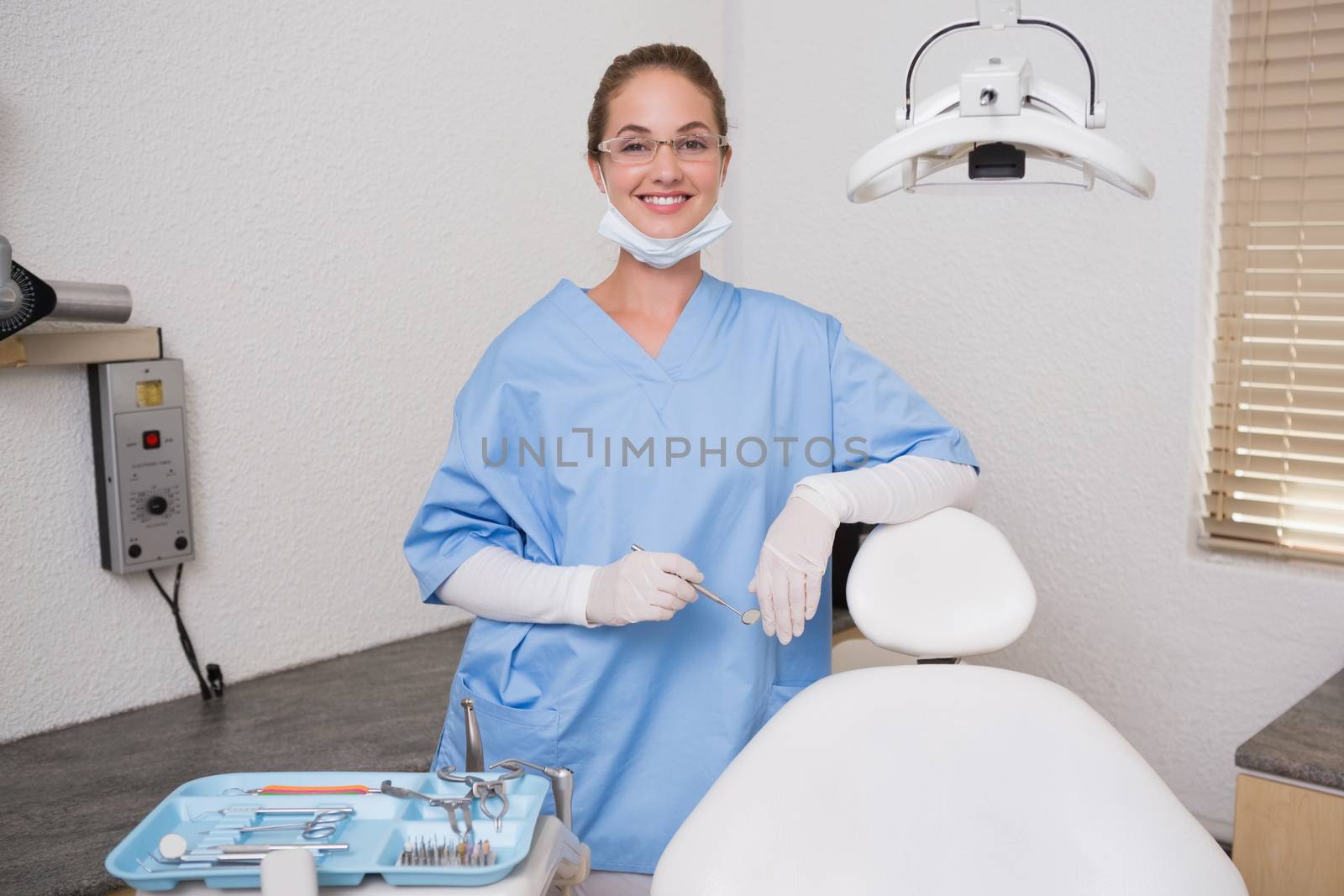 Dentist in blue scrubs smiling at camera at the dental clinic