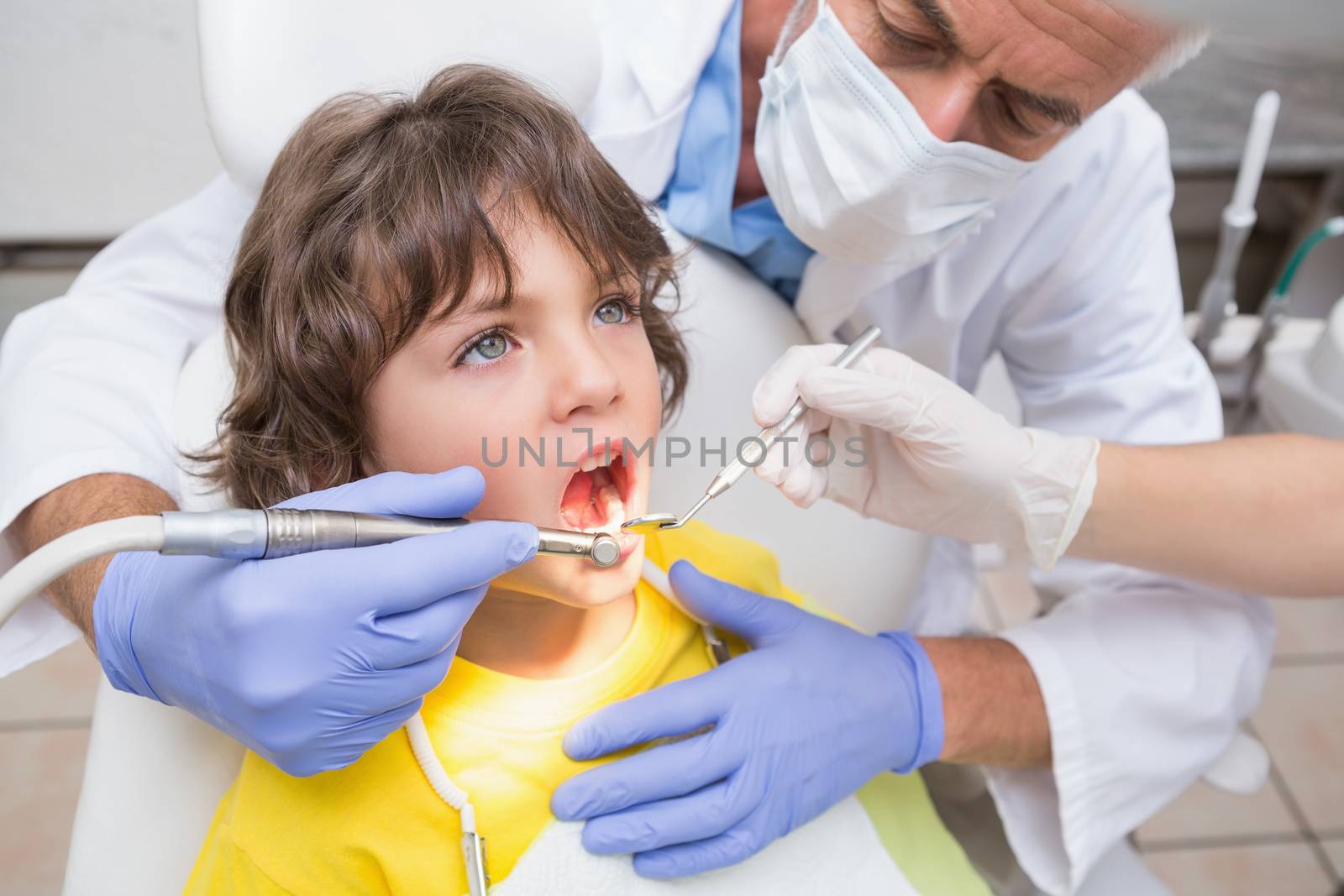 Pediatric dentist examining a little boys teeth in the dentists chair by Wavebreakmedia