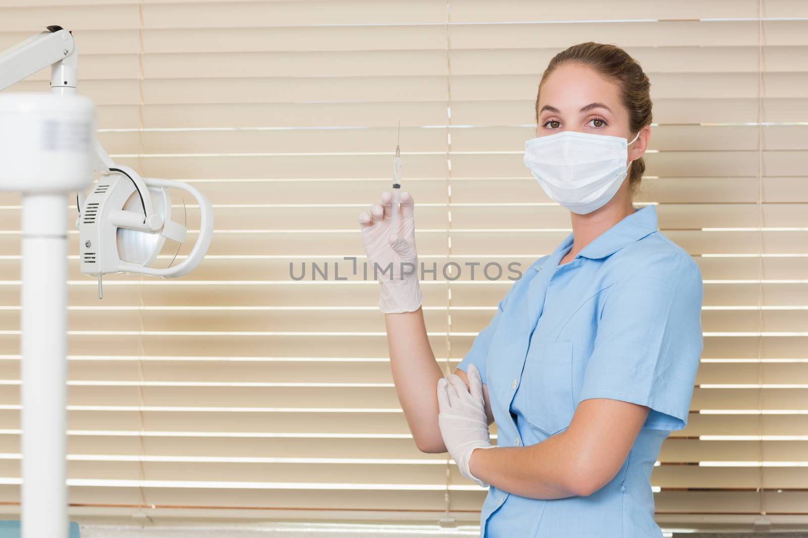 Dental assistant holding injection looking at camera by Wavebreakmedia