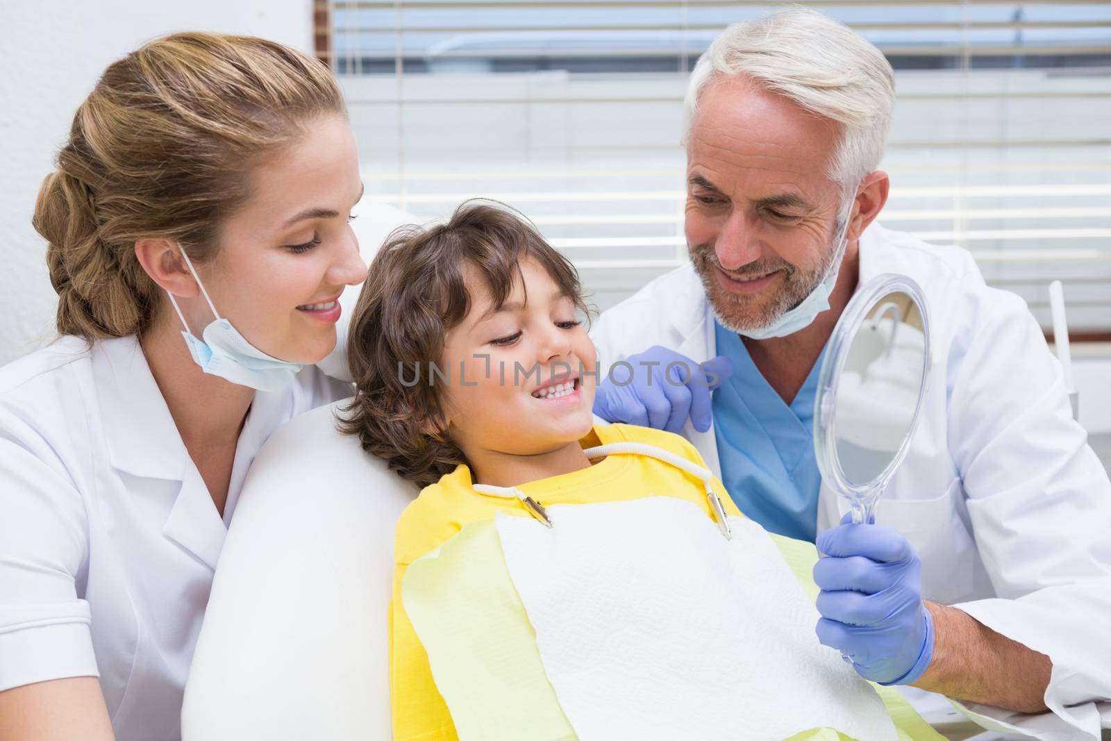 Pediatric dentist showing little boy how to brush his teeth at the dental clinic