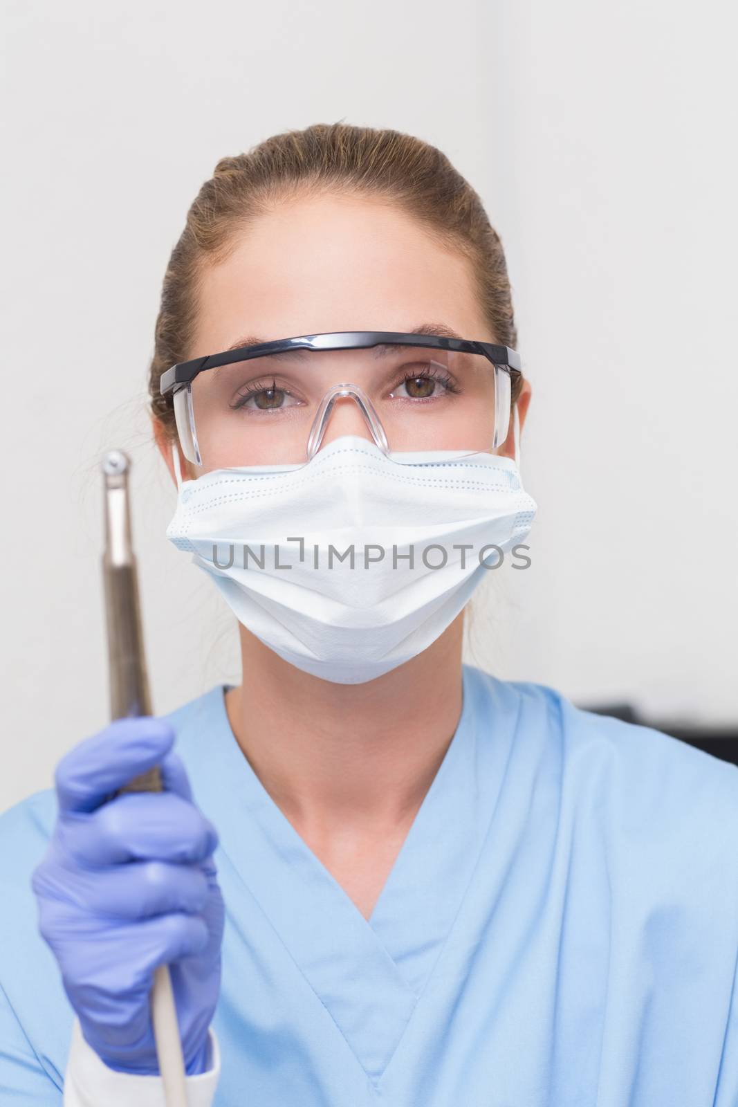 Dentist in blue scrubs holding dental drill by Wavebreakmedia